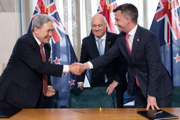 David Seymour, leader of the libertarian-ACT party (R), shakes hands with Winston Peters, leader of NZ First (L), as New Zealand's incoming Prime Minister Christopher Luxon looks on after signing an agreement to form a three-party coalition government at Parliament in Wellington on Nov. 24, 2023. (Marty Melville/AFP via Getty Images)