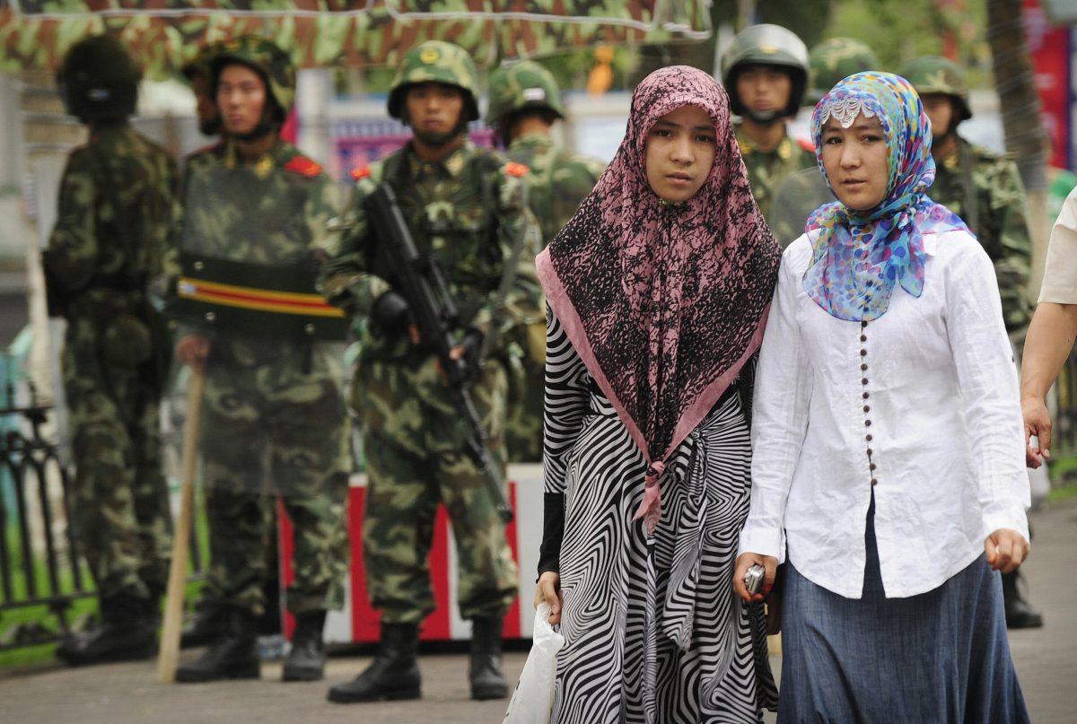 Two ethnic Uighur women pass Chinese paramilitary policemen standing guard outside the Grand Bazaar in Urumqi in China's Xinjiang region on July 14, 2009. (Peter Parks/AFP/Getty Images)