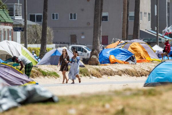 Women walk past homeless encampments in Venice Beach in Los Angeles on June 8, 2021. (John Fredricks/The Epoch Times)