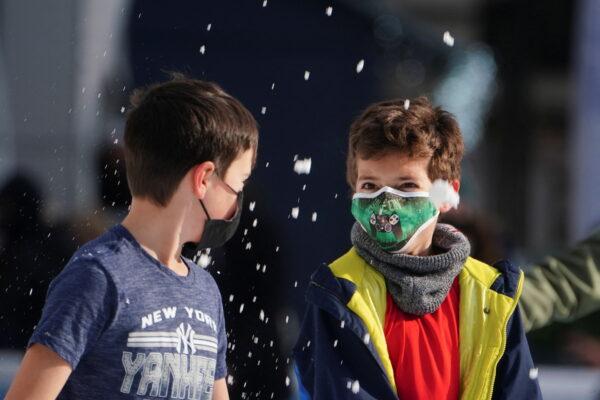 Children wearing protective masks toss snow at each other as they skate at Bryant Park during the COVID-19 pandemic in Manhattan on Jan. 14, 2022. (Carlo Allegri/Reuters)