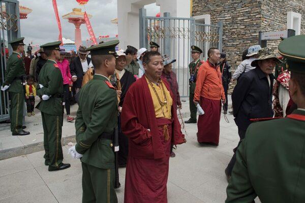 Chinese paramilitary police (in green uniforms) secure an exit as Tibetans monks (C) walk out from a stadium at the end of a local government sponsored festival in Yushu, in the China's northwestern Qinghai Province, on July 25, 2016. (Nicolas Asfouri/AFP via Getty Images)
