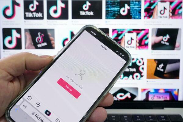 A sign-up page for the application TikTok is shown on a cellphone in front of a screen with logos for the company in Sydney on April 4, 2023. (Rick Rycroft/AP Photo)