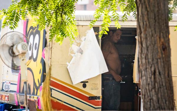 A man smokes a cigarette in a homeless RV encampment in the Venice area of Los Angeles on Nov. 10, 2021. (John Fredricks/The Epoch Times)