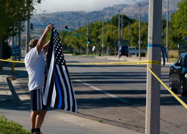 A local resident waves a Thin Blue Line flag in support of a deputy who was fatally wounded in Palmdale, Calif., on Sept. 17, 2023. The sheriff's department deputy died after he was shot in his patrol car by an unknown assailant on Sept. 16, and an investigation is underway. (Richard Vogel/AP Photo)
