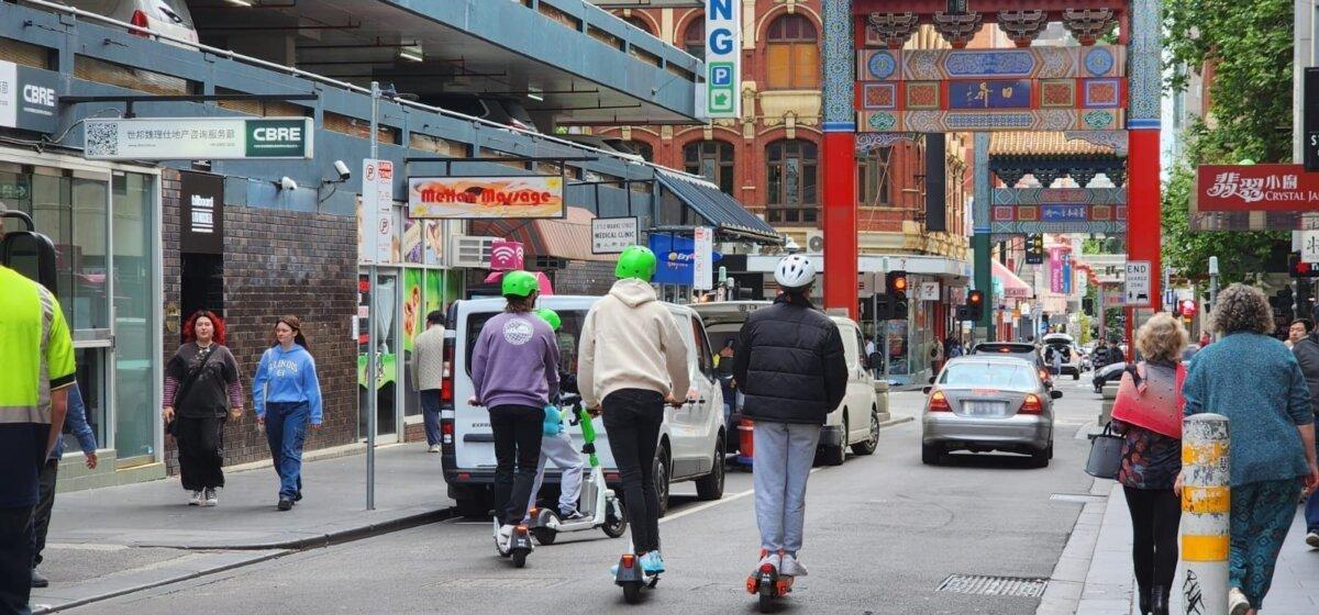 Three young people ride e-scooters towards Chinatown in Melbourne, Australia, on Oct. 28, 2023. (Susan Mortimer/The Epoch Times)