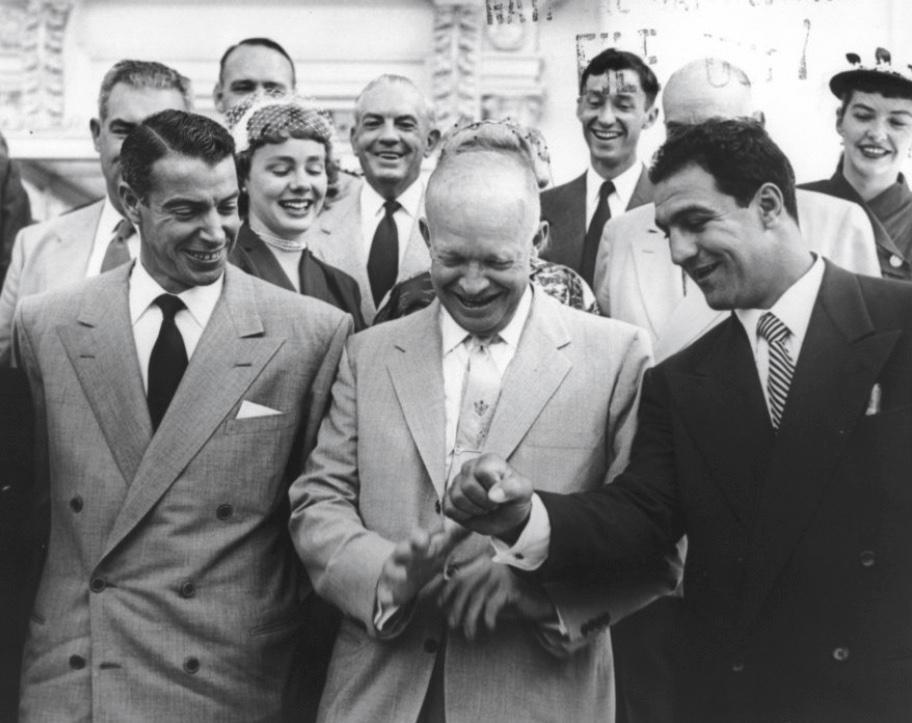 A photograph of Marciano displaying his fist of fame to President Dwight D. Eisenhower and World Series champion Joe DiMaggio (L) in 1953. (Public Domain)