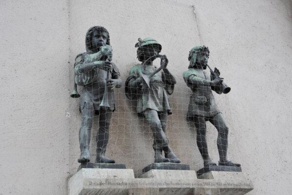 Three bronze figures, on the wall of the city gate on Neuhauser Street, of boys playing horns in Munich, Bavaria. (Pictor Pictures/Shutterstock)