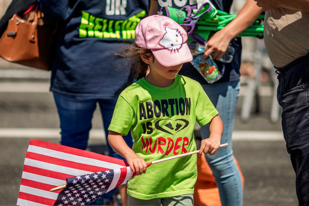 A child in an evangelical Christian group wears a pro-life T-shirt and carries an American flag during the annual LA Pride Parade in West Hollywood, Calif., on June 9, 2019. (DAVID MCNEW/AFP via Getty Images)