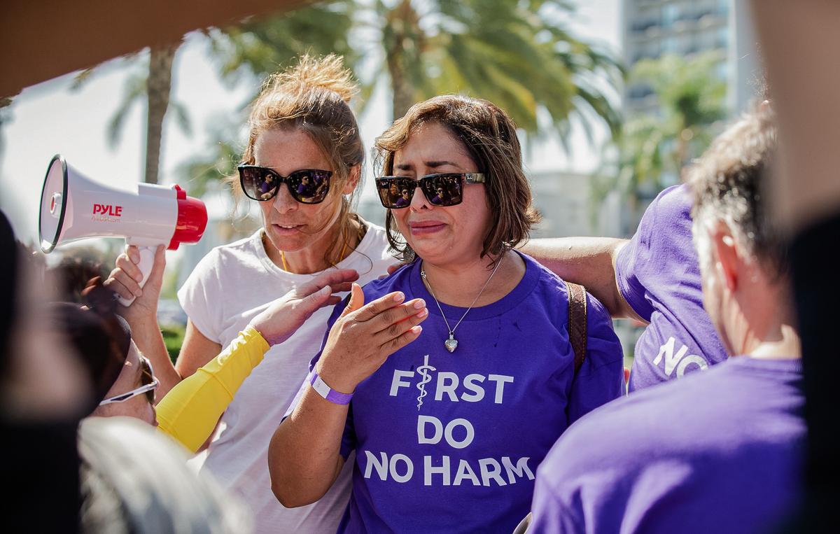 Abigail Martinez (R), the mother of a transgender teen who committed suicide, sheds tears as Erin Friday comforts her and transgender activists block TV cameras from capturing her story in Anaheim, Calif., on Oct. 8, 2022. (John Fredricks/The Epoch Times)