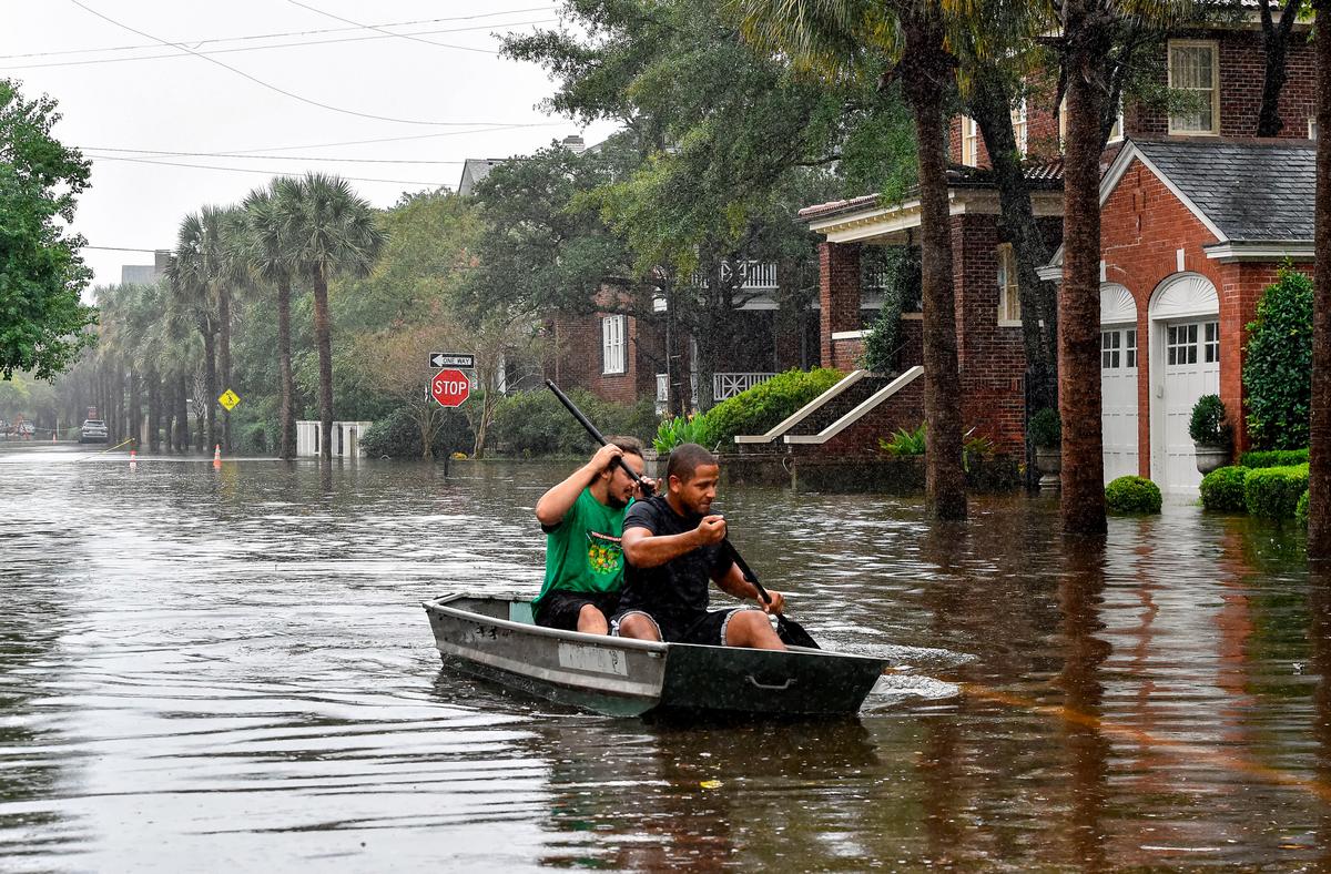 Two men row a boat on a flooded street in Charleston, S.C., on Oct. 4, 2015. Voters indicated that solving flooding issues was an important topic during the 2023 mayoral election. (Mladen Antonov/AFP via Getty Images)