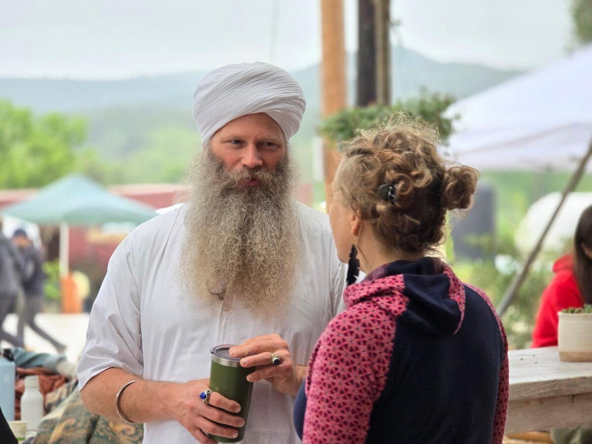 Kundalini Yoga teacher Jai Gopal speaks with a visitor during Confluence 2024 in Bandera, Texas, on April 5, 2024. (Allan Stein/The Epoch Times)